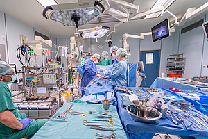 OP-Setting: Ärzte stehen am Patienten, im Vordergrund iegen Instrumente auf dem Tisch