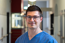 Porträt eines lächelnden Mannes mit Brille in einem Gang