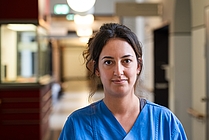 Porträt einer Frau im blauen Kasack auf einem Krankenhausflur